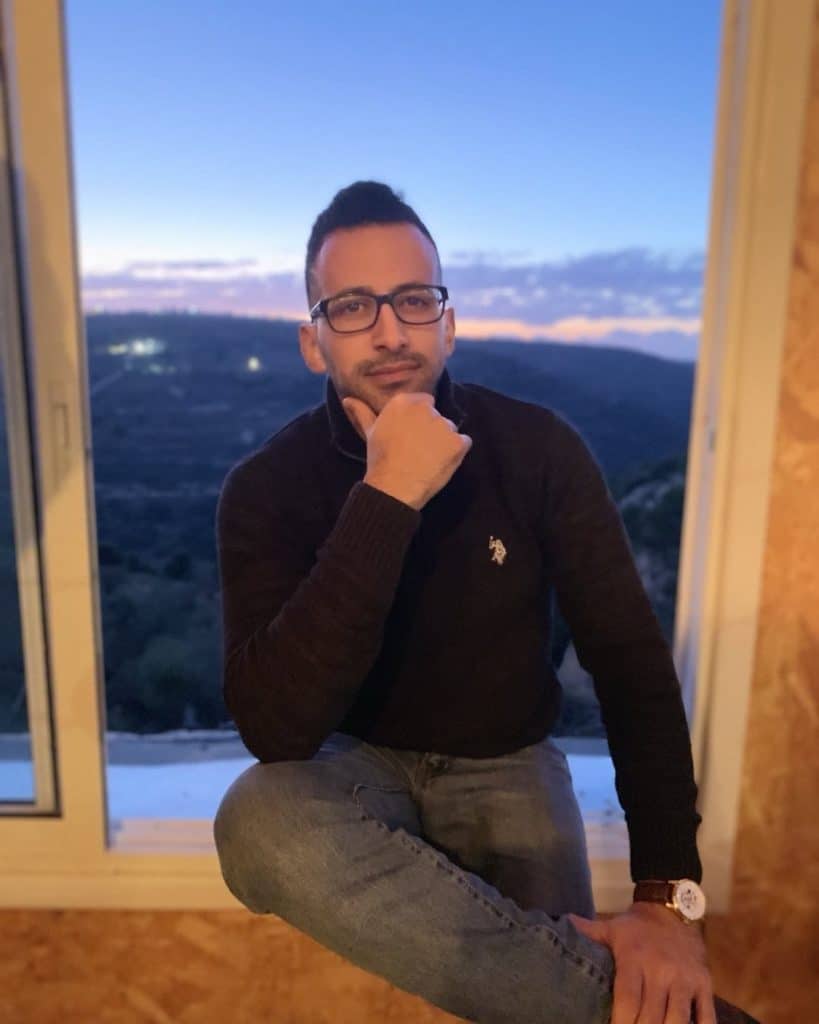 Ahmed Hmeedat, founder of the Palestinian Artists Consortium, sitting by a window at dusk